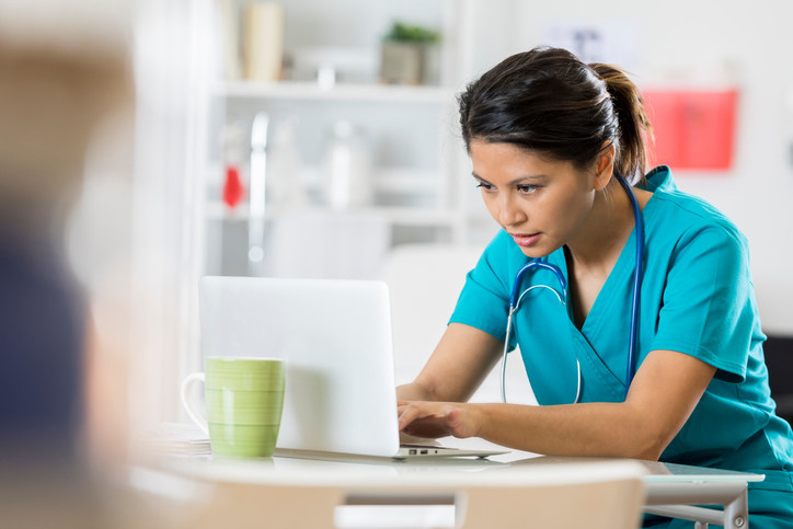 Female healthcare professional uses a laptop. Hospital Efficiency is crucial.